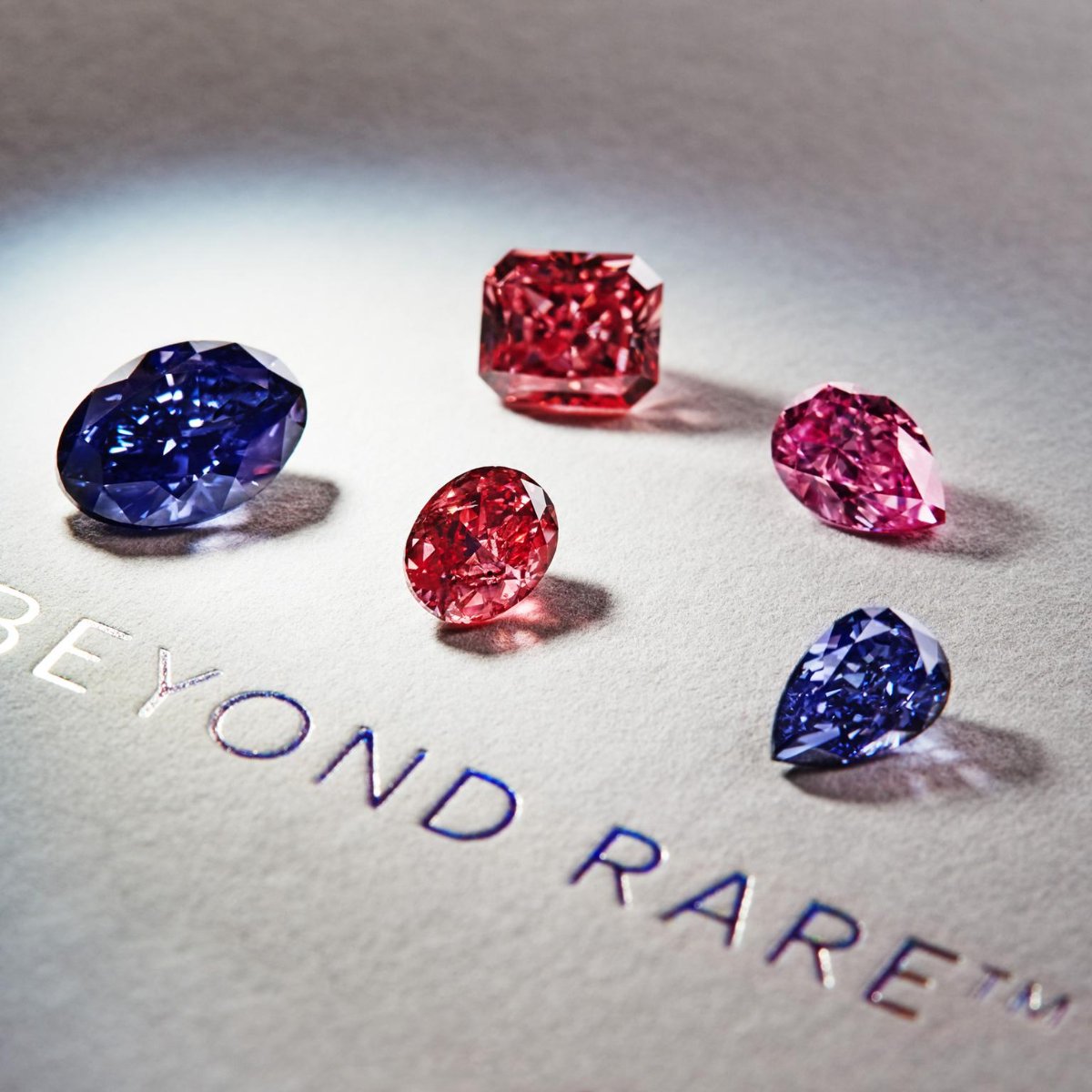 Blue, red and pink diamonds on a pale card embossed with the words Beyond Rare
